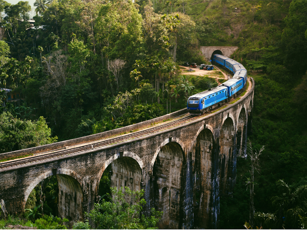 Blue passenger train crossing the Nine Arch Bridge